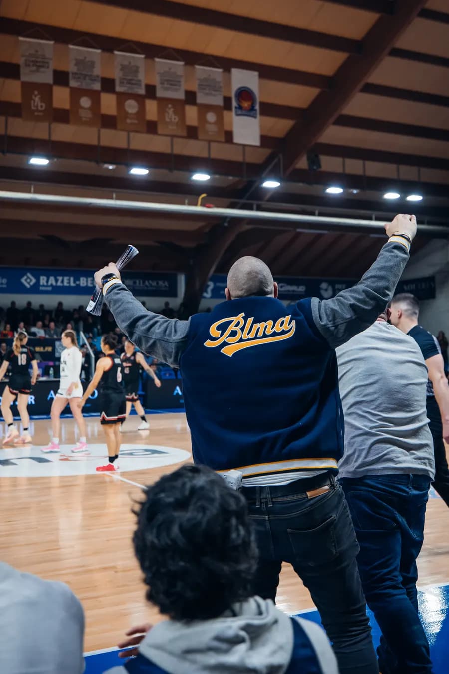 Un tifoso con la giacca BLMA festeggia un canestro in tribuna